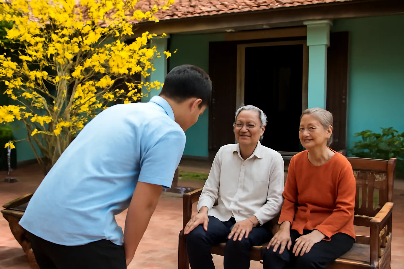 Chàng trai cúi chào ông bà ngồi trên ghế gỗ trong sân nhà có cây mai